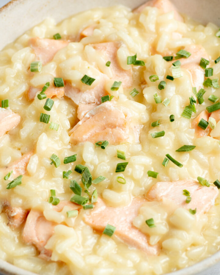 Creamy salmon risotto with chives in a beige bowl.