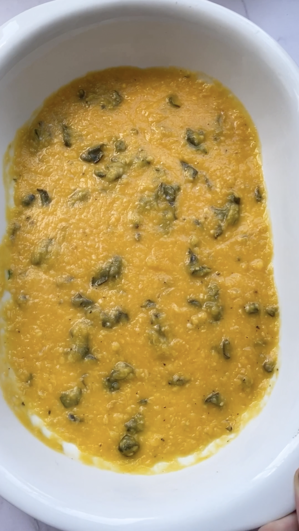 A white ovenproof dish filled with the butternut squash and sage sauce.