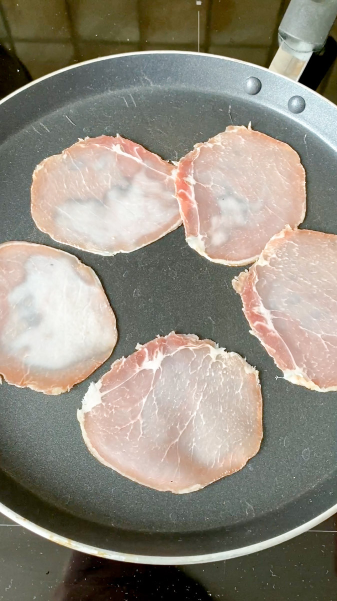 Bacon slices in a frying pan.