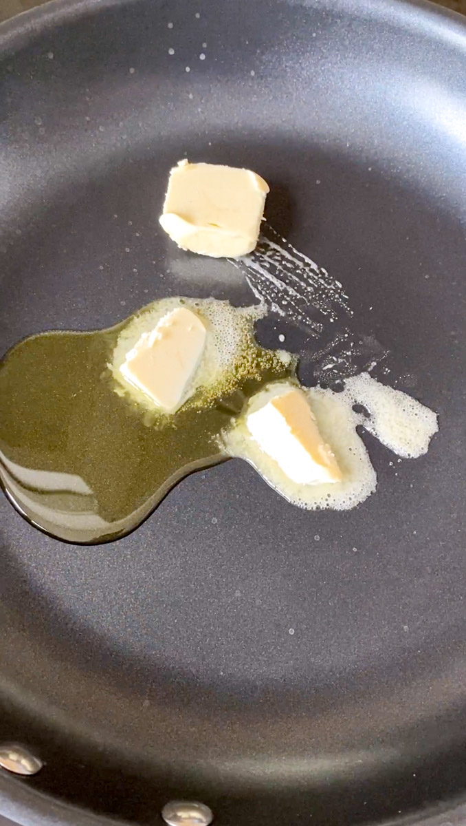 Huile d'olive et plusieurs morceaux de beurre en train de fondre dans une poêle noire.