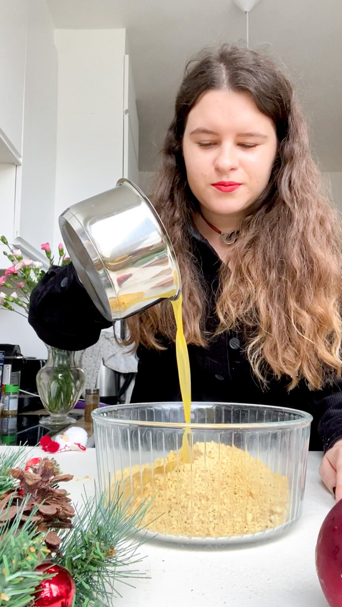 Marie pours the pan of melted butter into the bowl of powdered crackers.