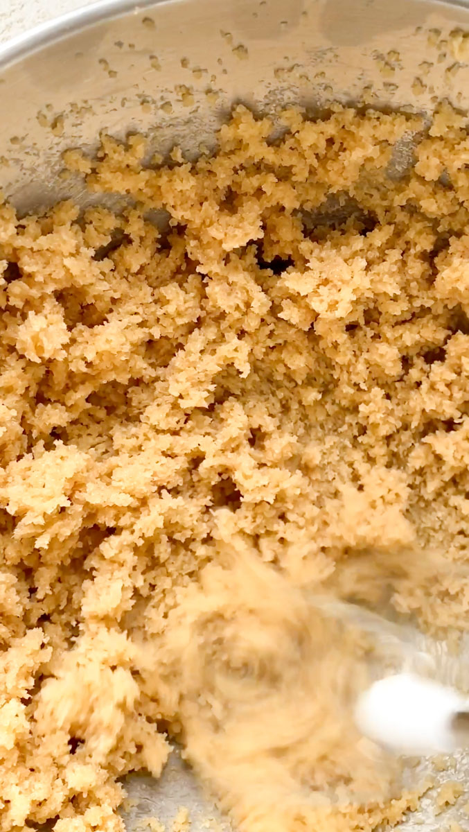 An electric mixer creaming the butter and light brown sugar.