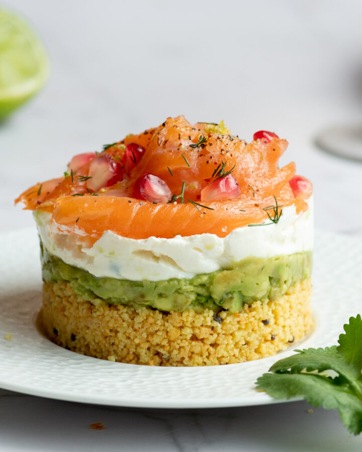 Cheesecake au saumon fumé, avocat et fromage frais dans une assiette blanche.