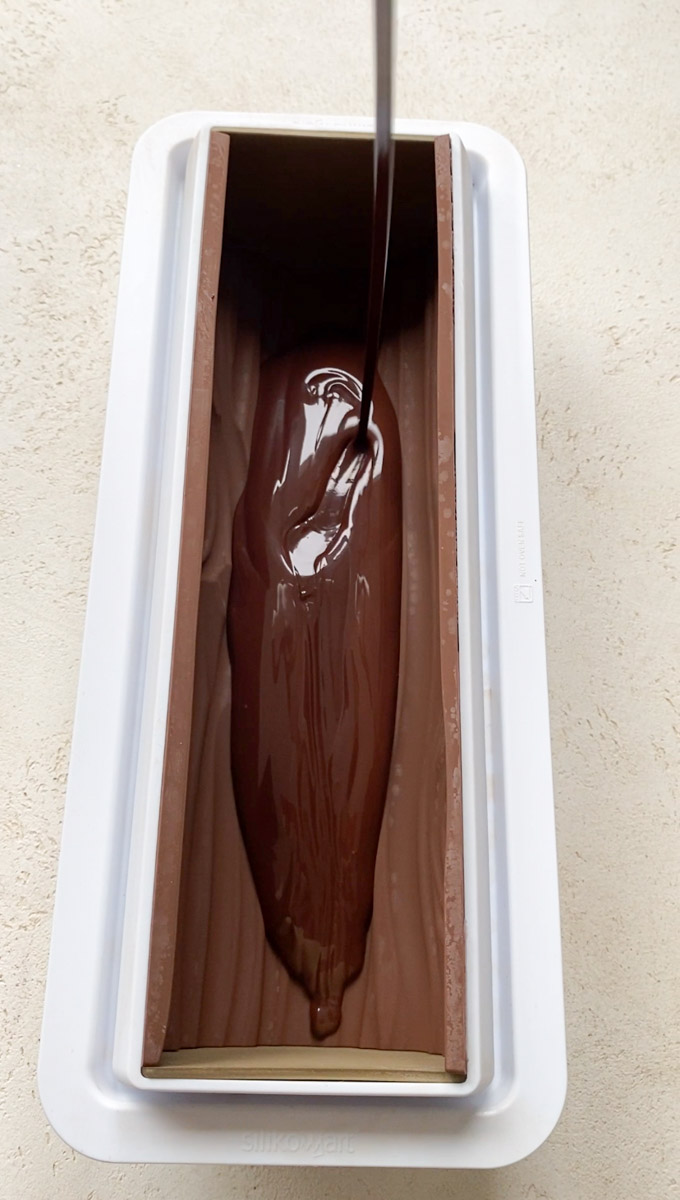 Chocolat fondu versé dans le moule à bûche.