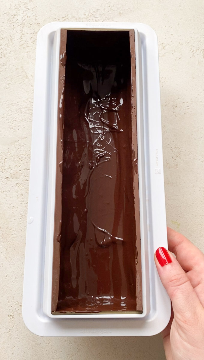 Moule à bûche rempli de manière homogène de chocolat fondu.