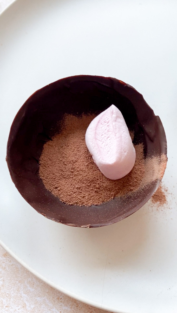 Half a sphere garnished with cocoa powder and a marshmallow.