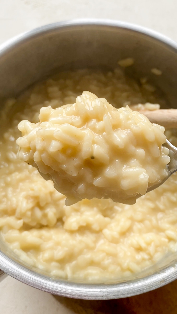 Cooked creamy risotto hold by a spoon.