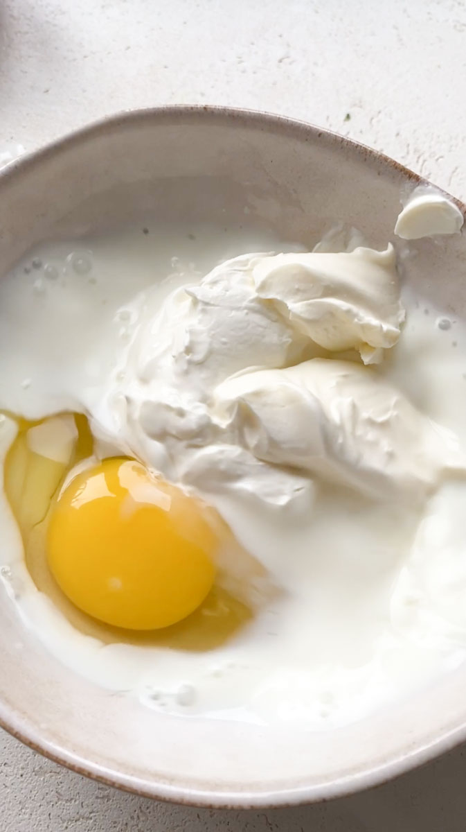 One egg with milk and creme fraiche, in a beige bowl.