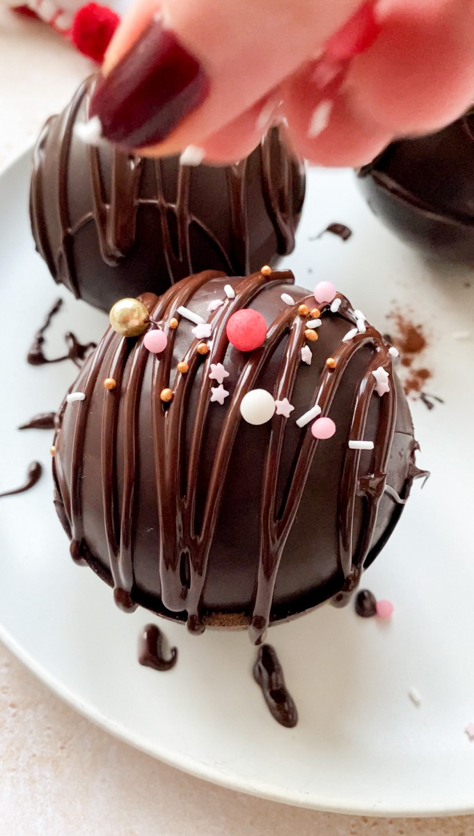 Edible pink decorations added on top of the chocolate sphere.