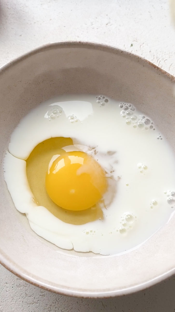 Un œuf avec du lait dans un bol beige.
