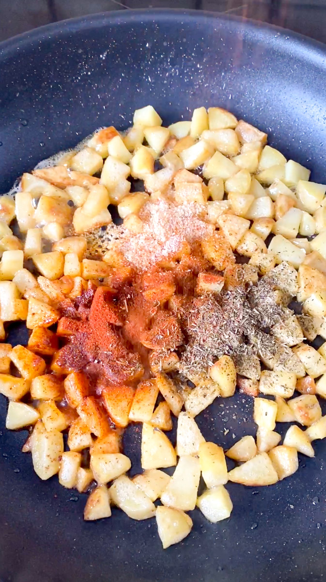 Paprika, ail en poudre, oignon en poudre, herbes de Provence et piment de Cayenne rajoutés aux cubes de pomme de terre dans la poêle.