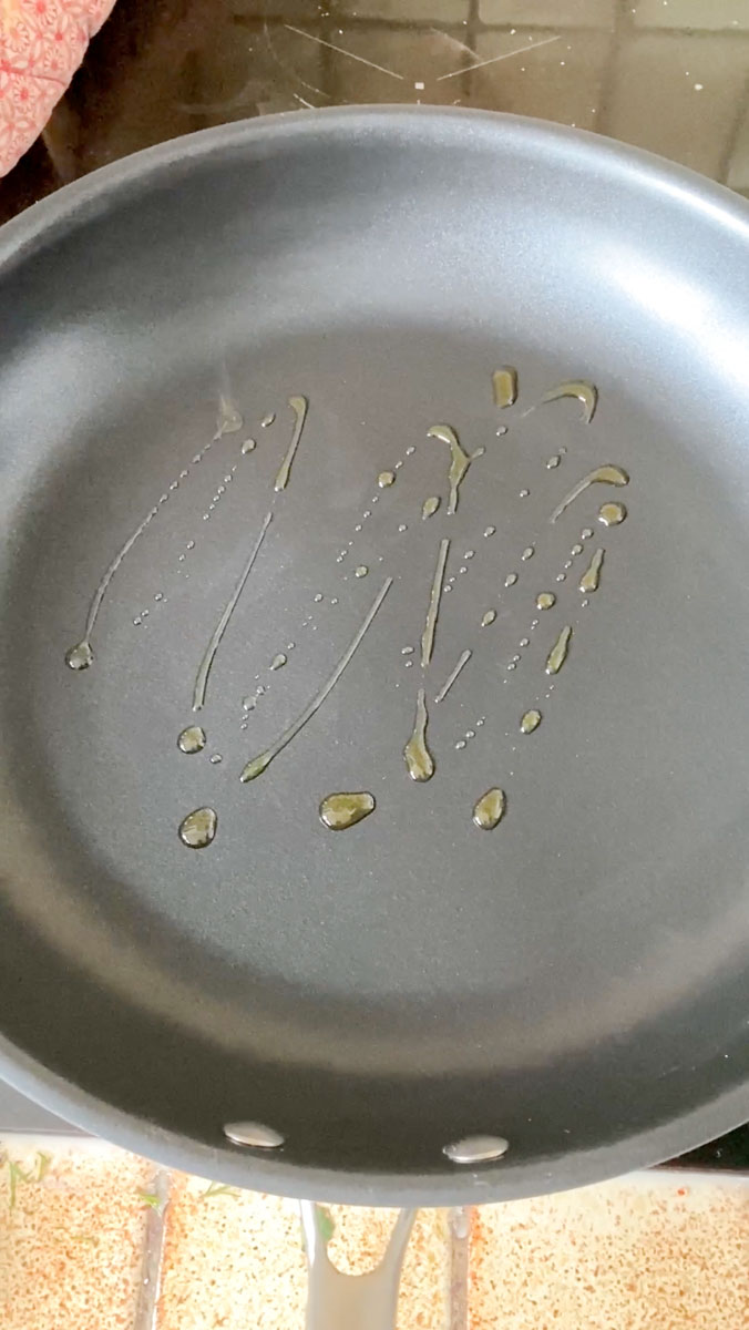 Olive oil drizzled in a frying pan.