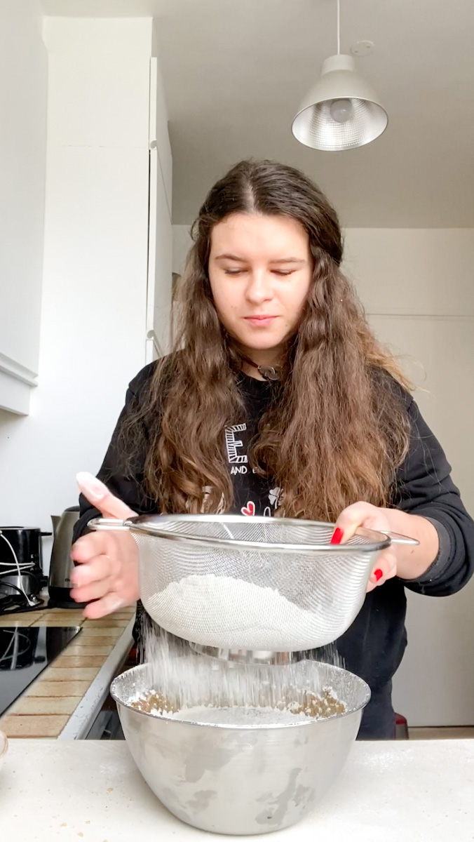 Marie sifting flour through a colander.