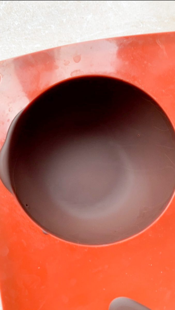 Chocolat durci dans un moule marron en forme de demi-sphère.