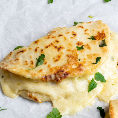 Naan façon Grilled Cheese avec du fromage fondant et du persil frais sur papier sulfurisé.
