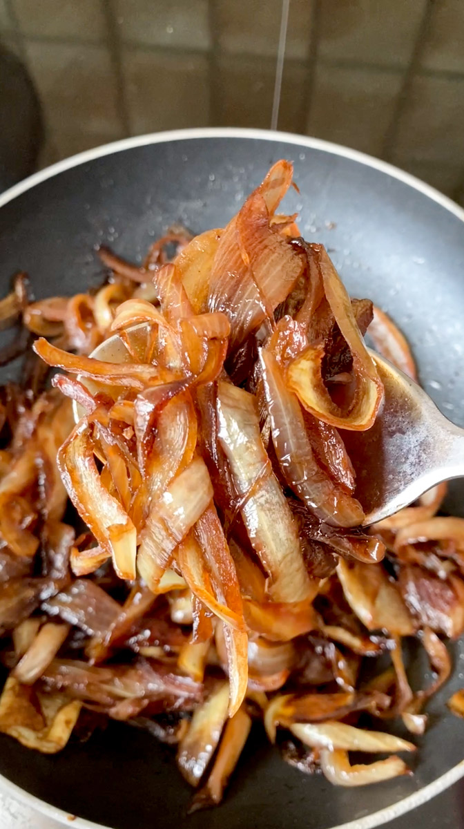 Onion confit ready, hold by a spoon.