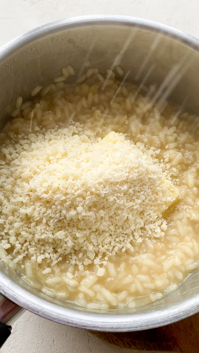 Freshly grated Parmesan cheese added to the saucepan of cooked risotto.