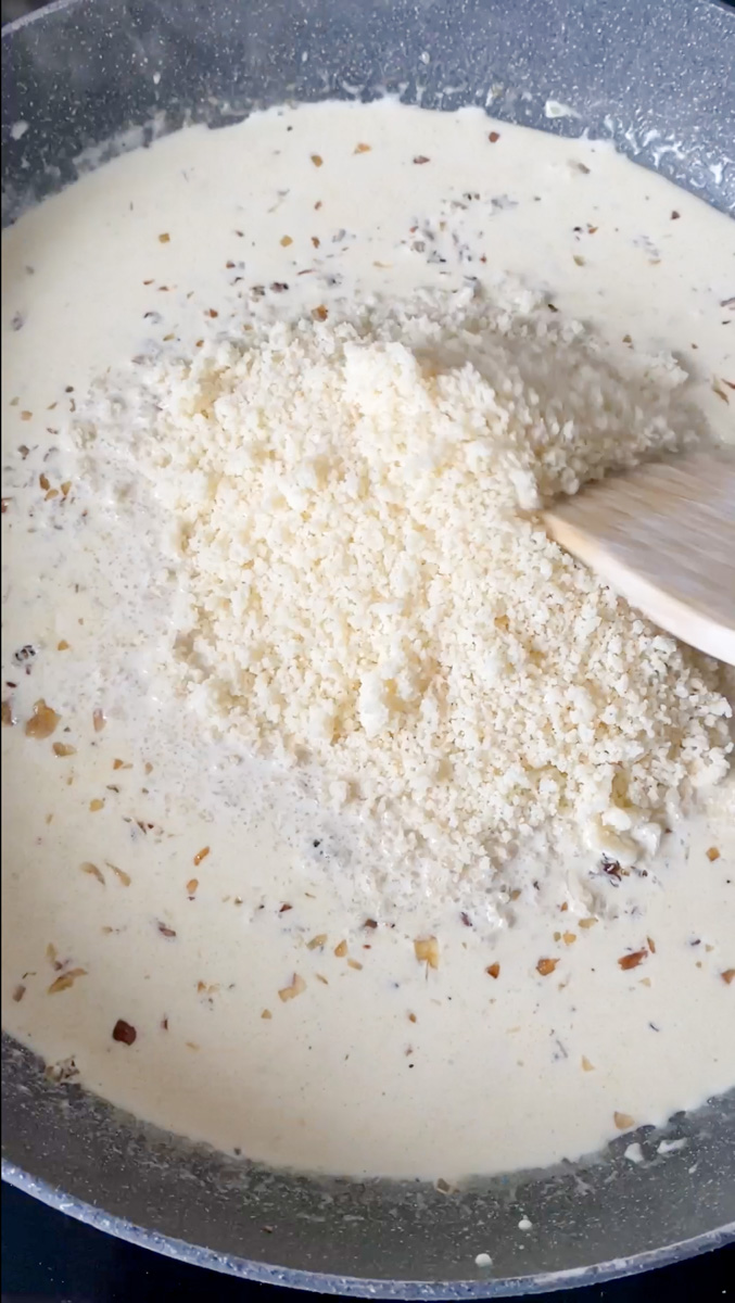 Freshly grated Parmesan cheese in the pan, with a wooden spoon.