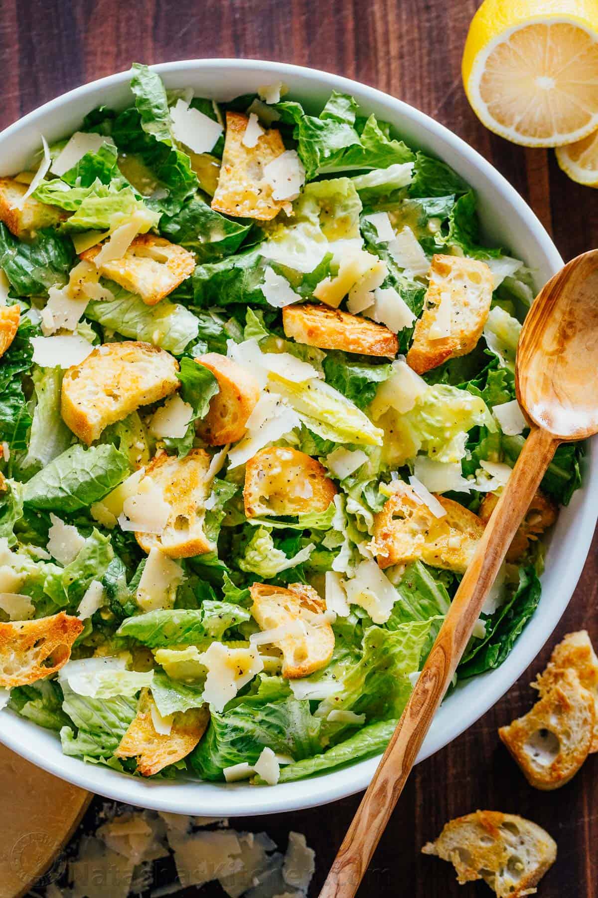 Caesar salad in a large plate with a wooden spoon.