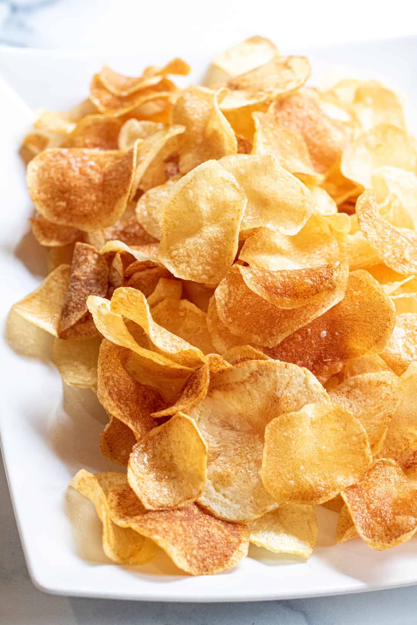 Crispy potato chips on a rectangular white plate.