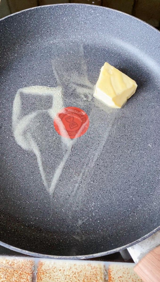 Butter melting in a grey pan.
