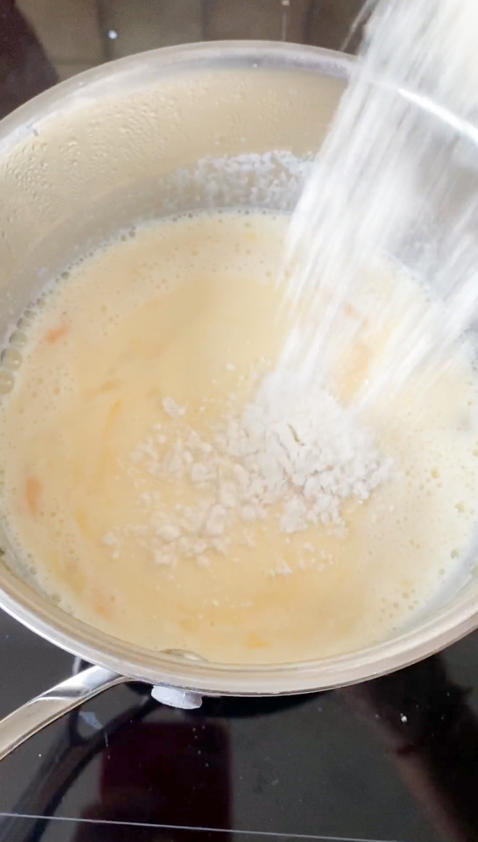 Ajout de farine à la casserole pour réaliser la crème pâtissière.