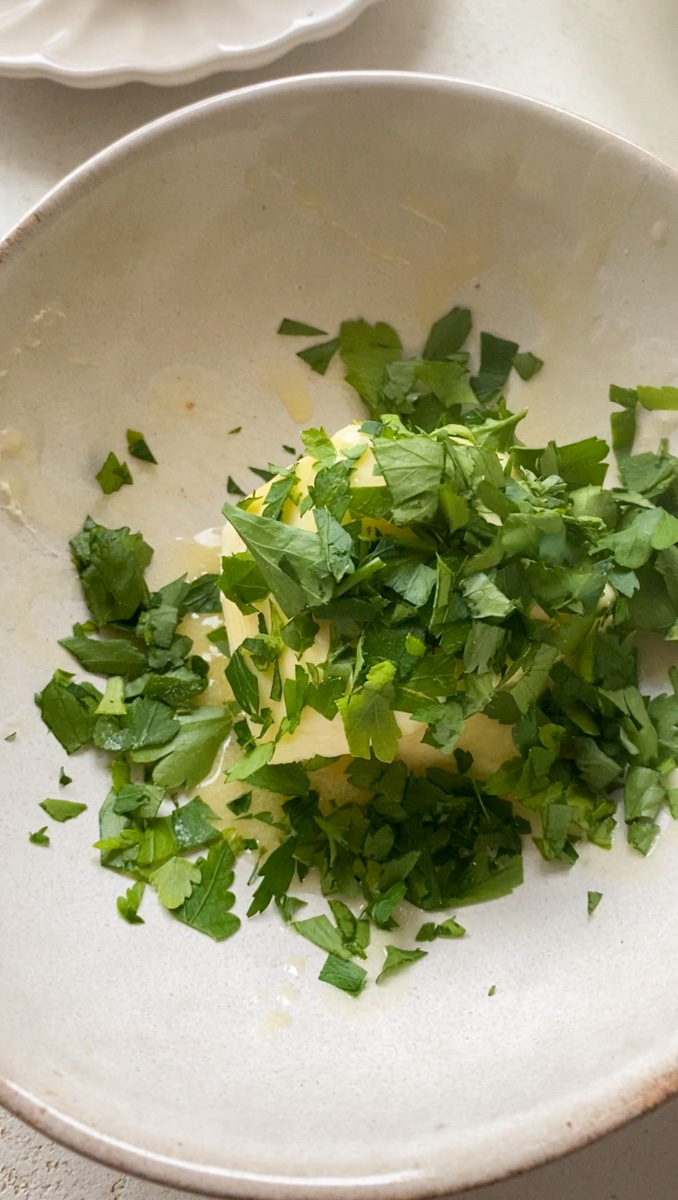 Soft butter with freshly chopped parsley in a beige bowl.