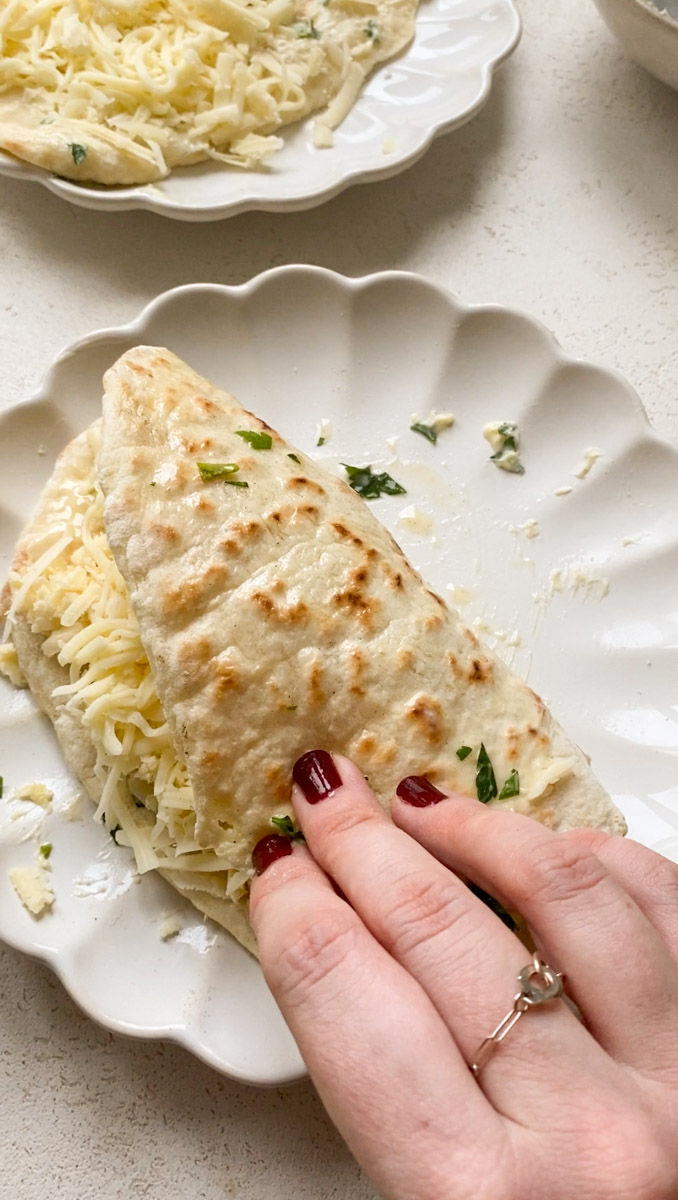 Naan folded over itself in a white plate.