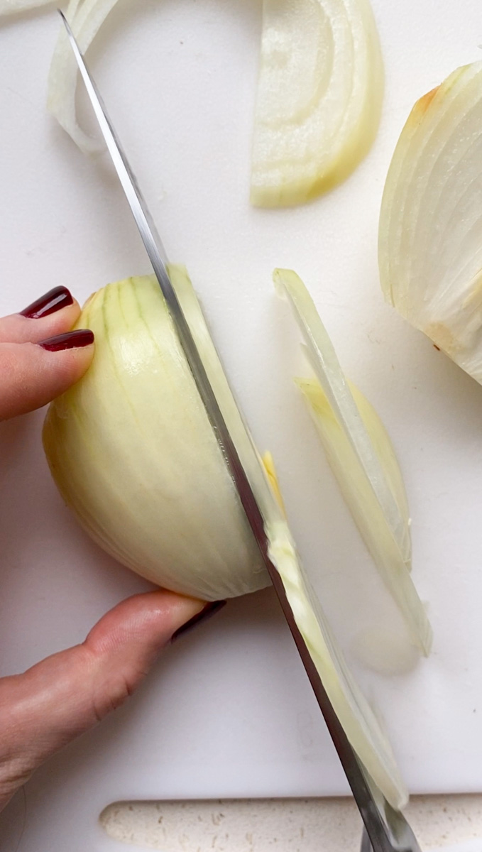 A knife cutting an onion in super thin strips.