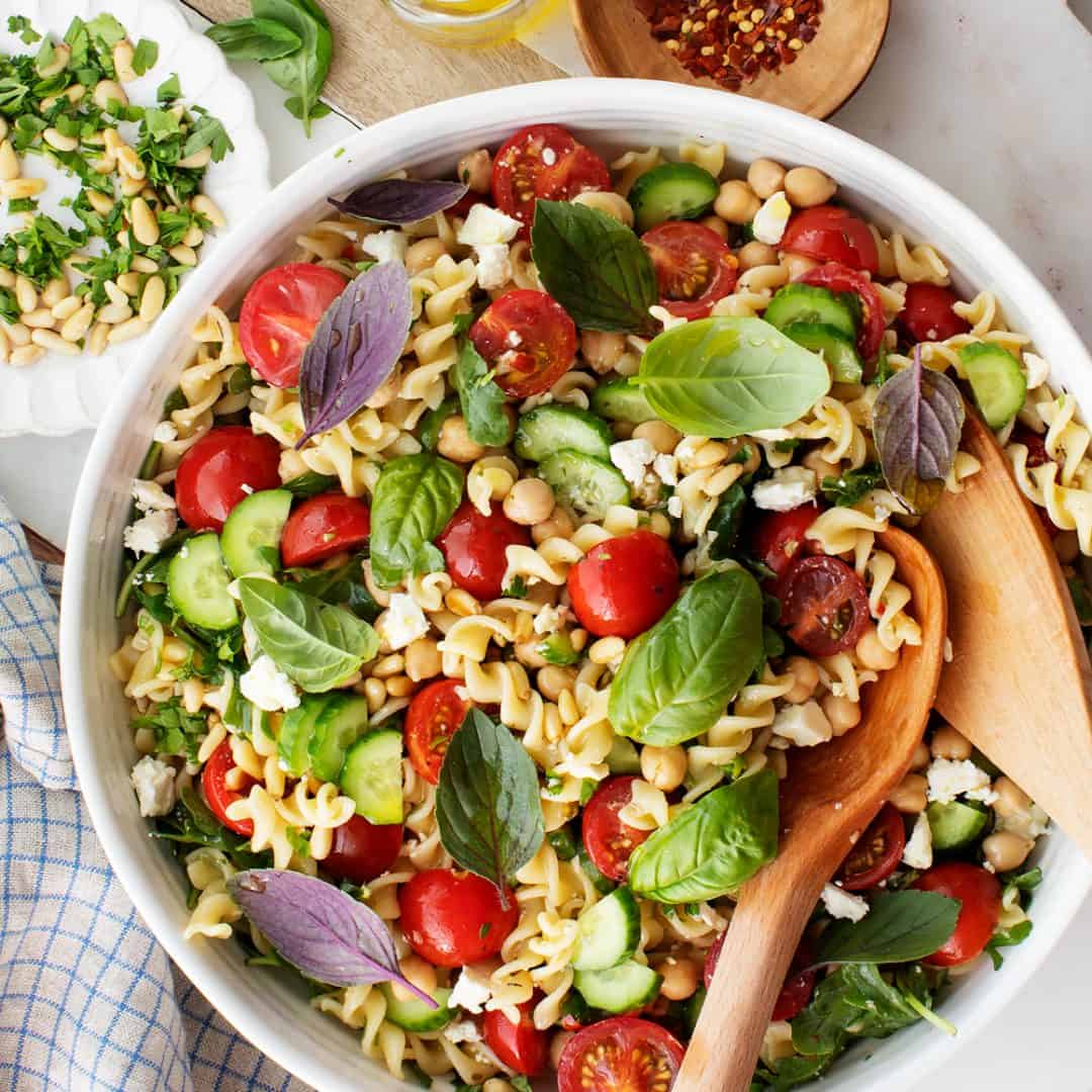 Pasta salad with cherry tomatoes, basil, chickpeas, arugula and feta cheese.