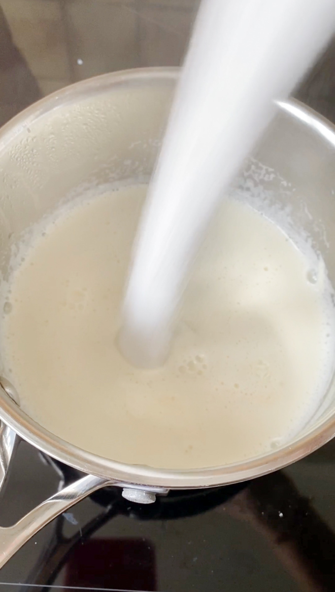 Ajout de sucre à la casserole pour réaliser la crème pâtissière.