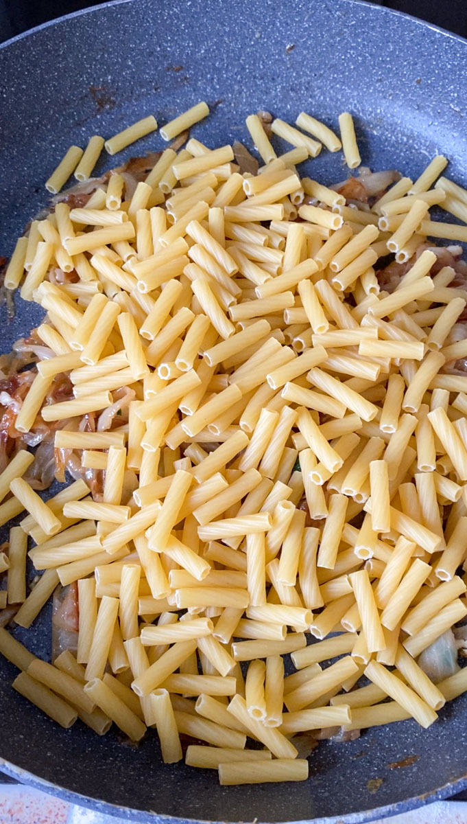Uncooked pasta added to the pan.