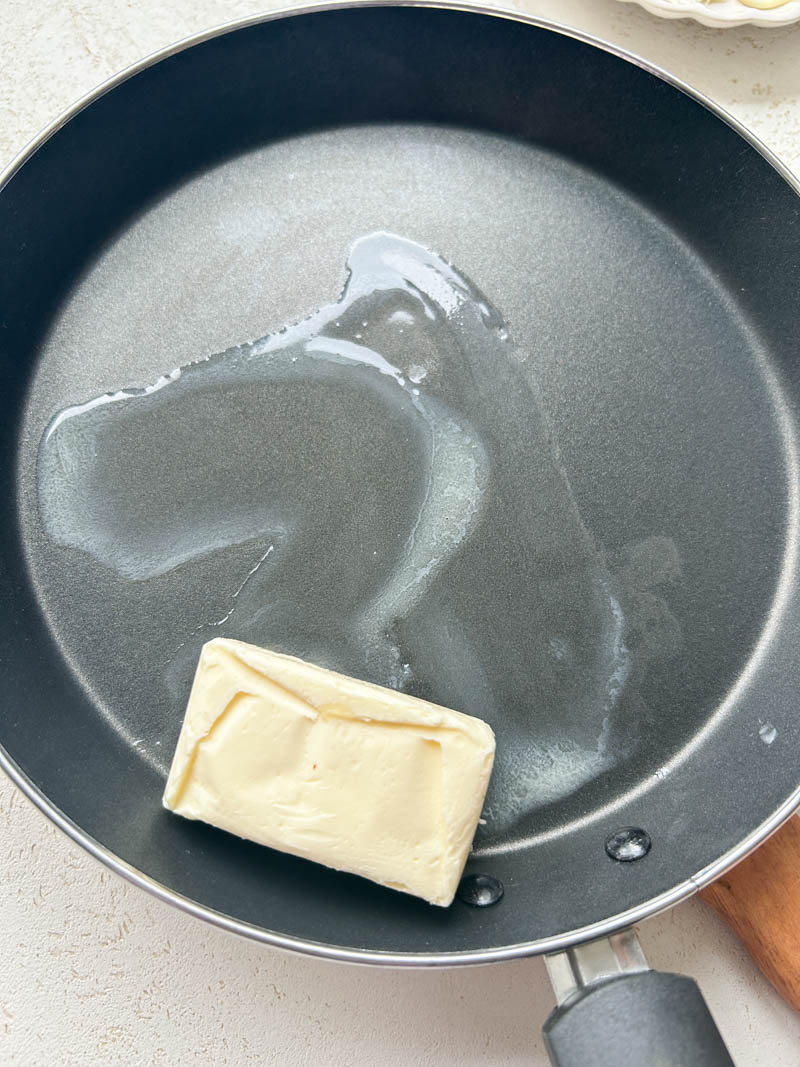 Un rectangle de beurre qui fond dans une petite poêle.