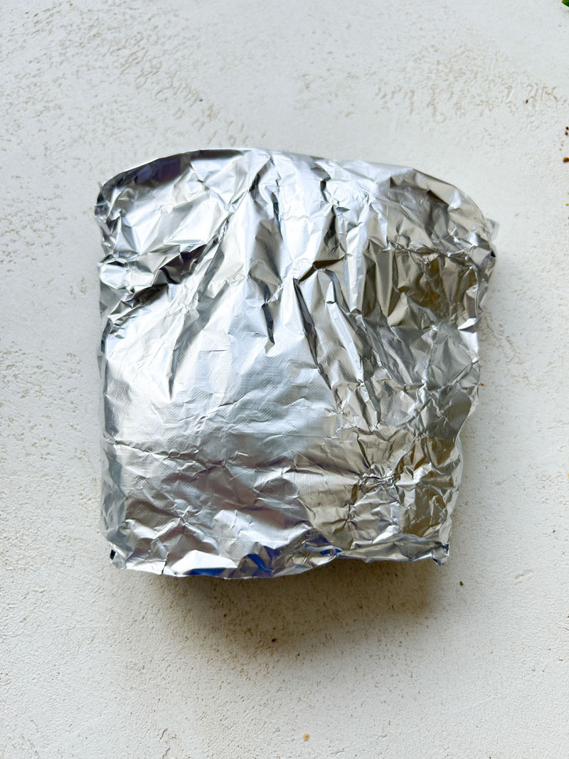 Aluminium foil closed, with chicken breasts inside.