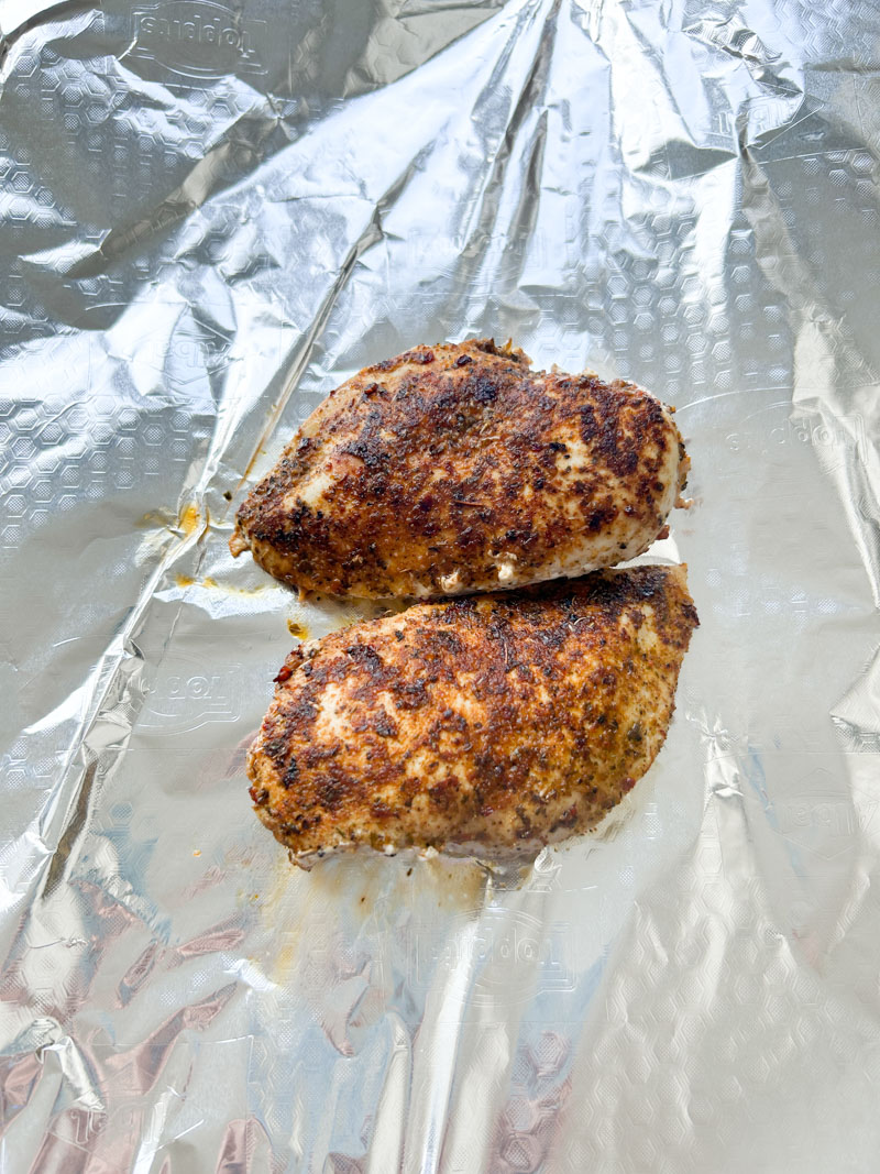 Two cooked chicken breasts in aluminium foil.