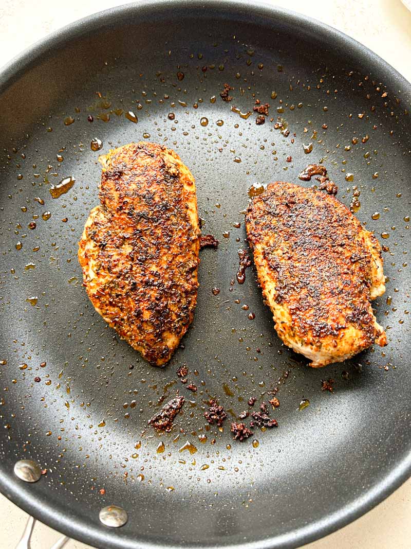 Cooked chicken breasts in the black frying pan.