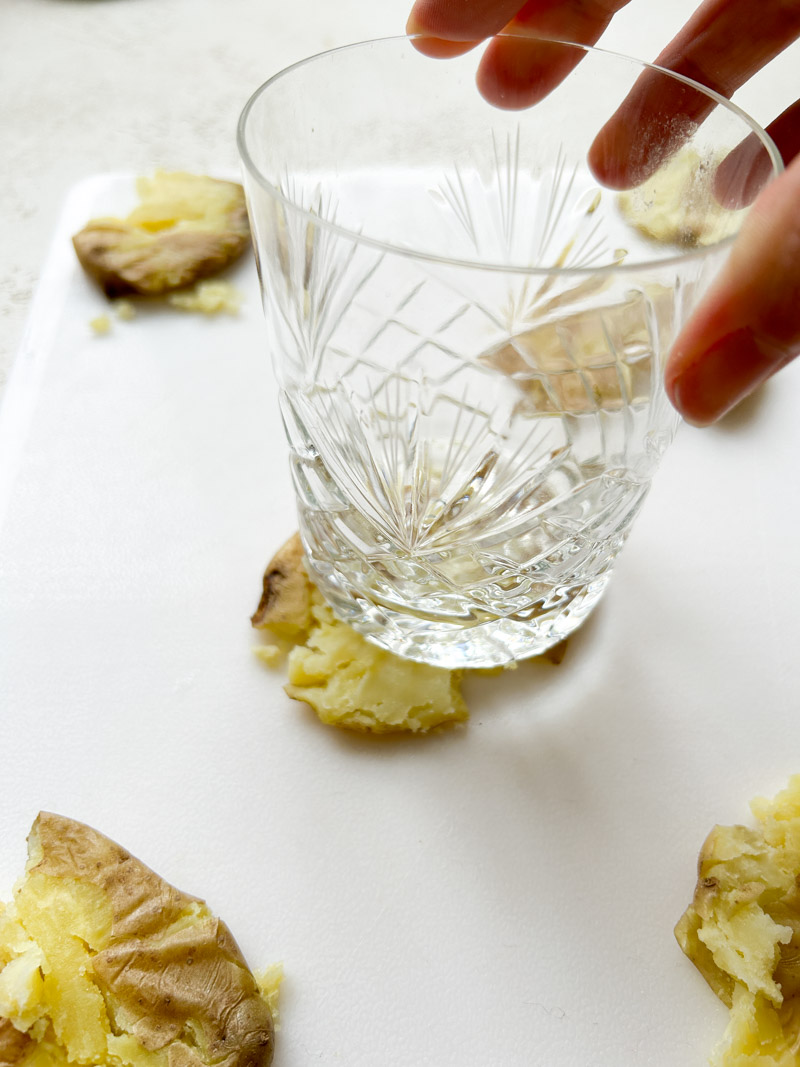 A hand holding a glass, crushing a potato.