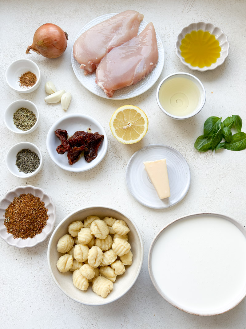 Les ingrédients du one pot poulet et gnocchi dans des bols blancs et beiges.