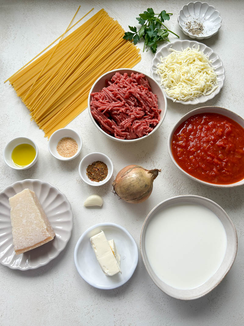 Les ingrédients du gratin de spaghettis dans des bols beiges et blancs.
