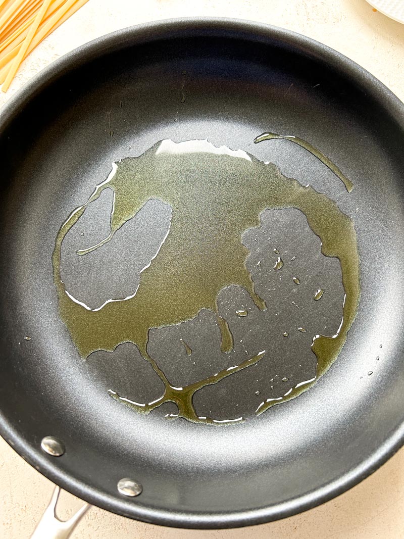 Olive oil in a black frying pan.