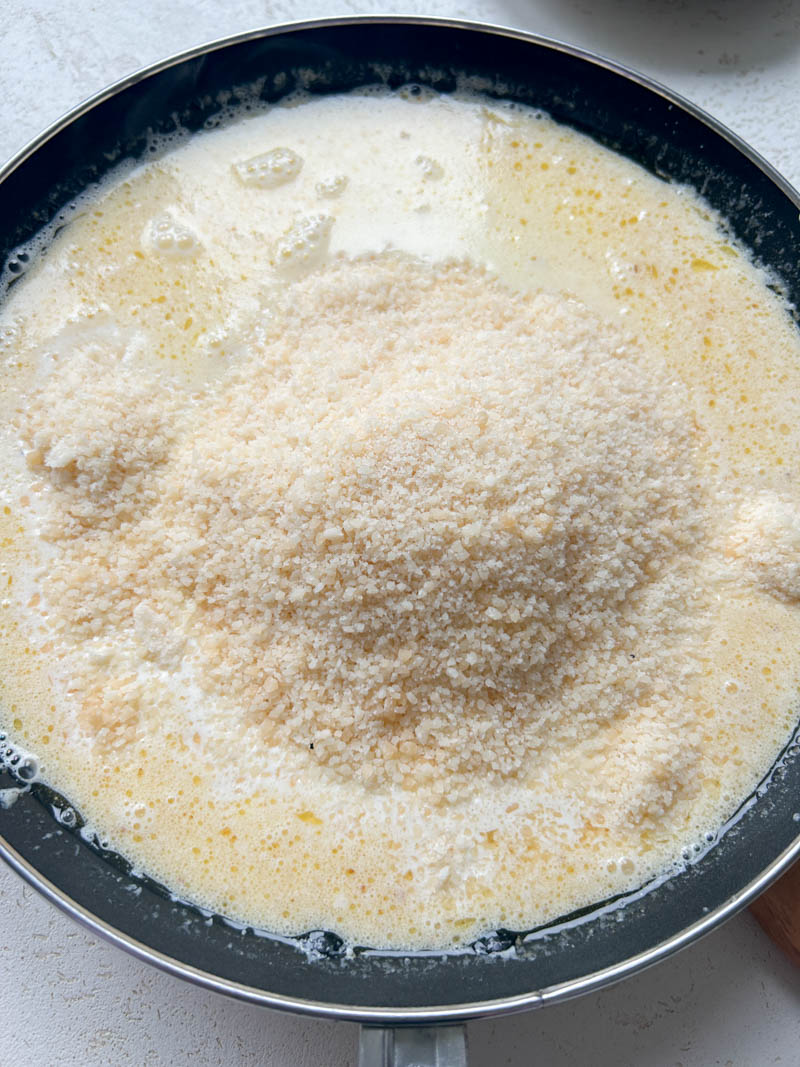 Crème et parmesan fraîchement râpé ajoutés à la poêle de beurre fondu et d'ail.