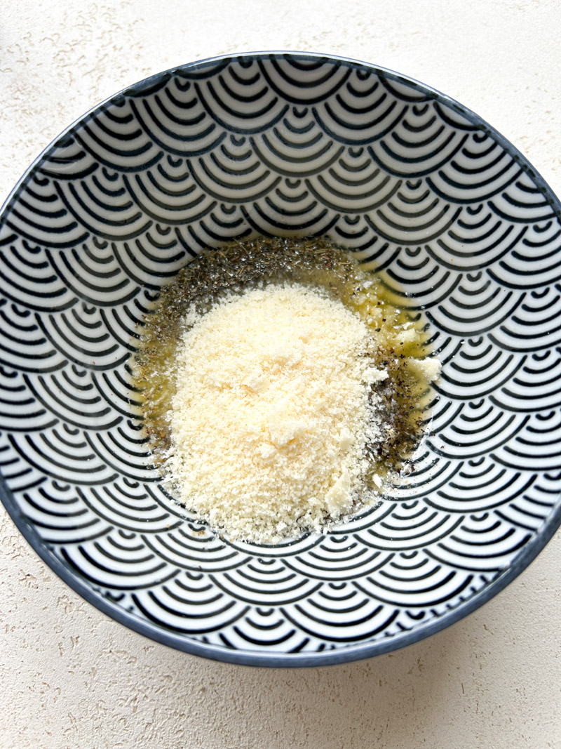 Freshly grated Parmesan cheese added to the blue bowl.