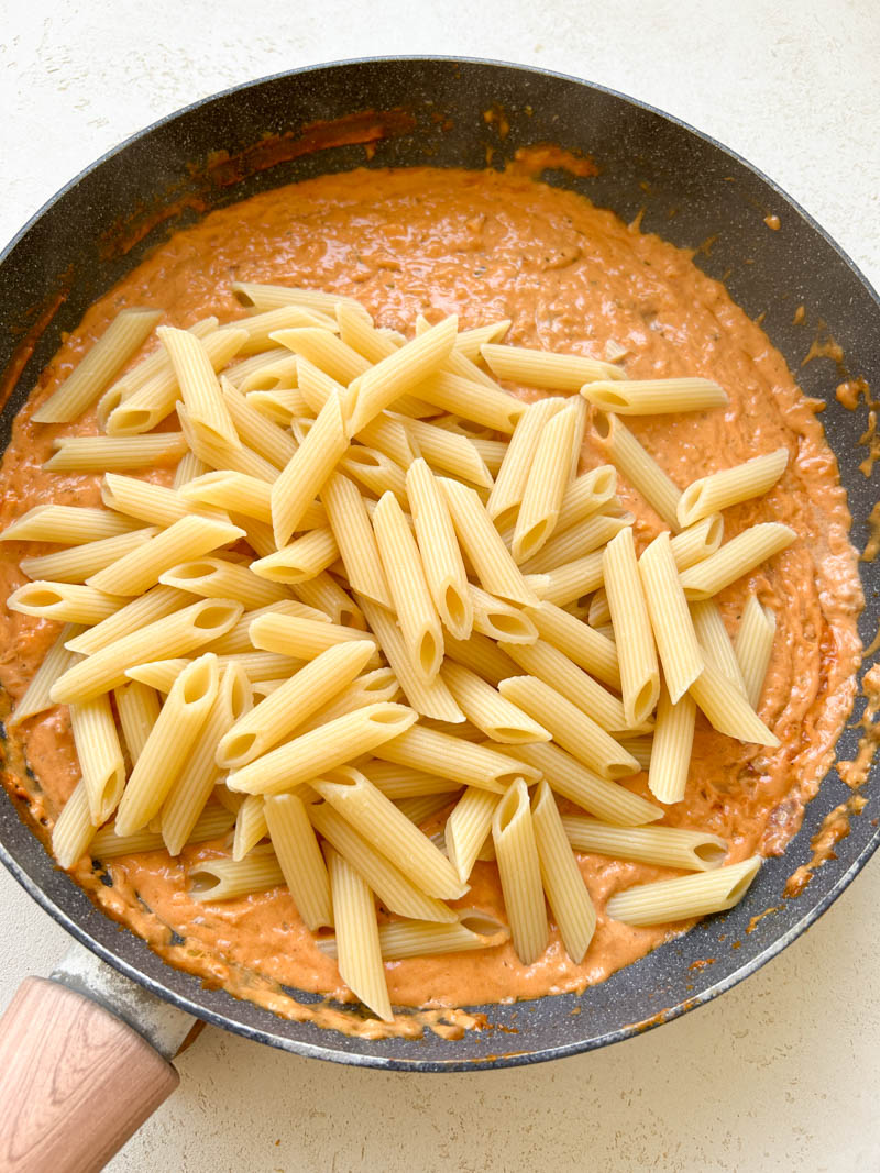 Cooked pasta added to the skillet of red sauce.