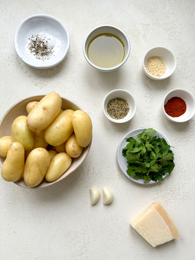 Ingrédients des pommes de terre à l'ail et au Parmesan dans des bols beiges et blancs.
