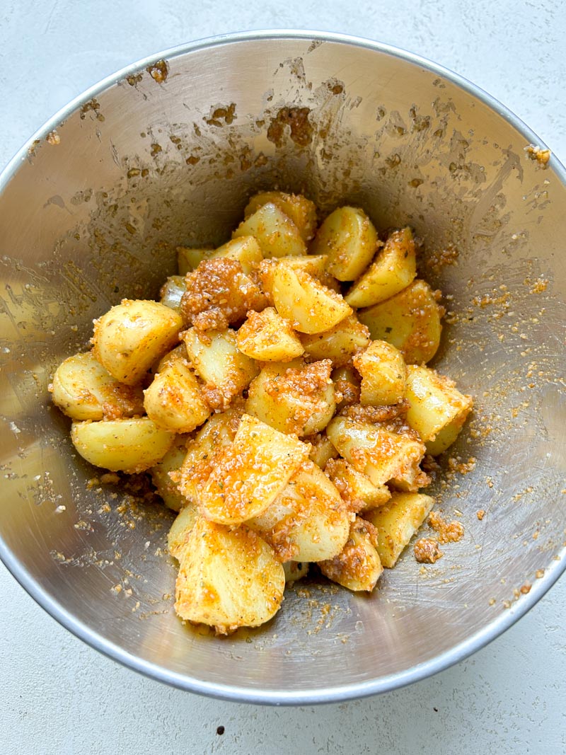 Potatoes perfectly coated with the Parmesan cheese mixture, in the grey bowl.