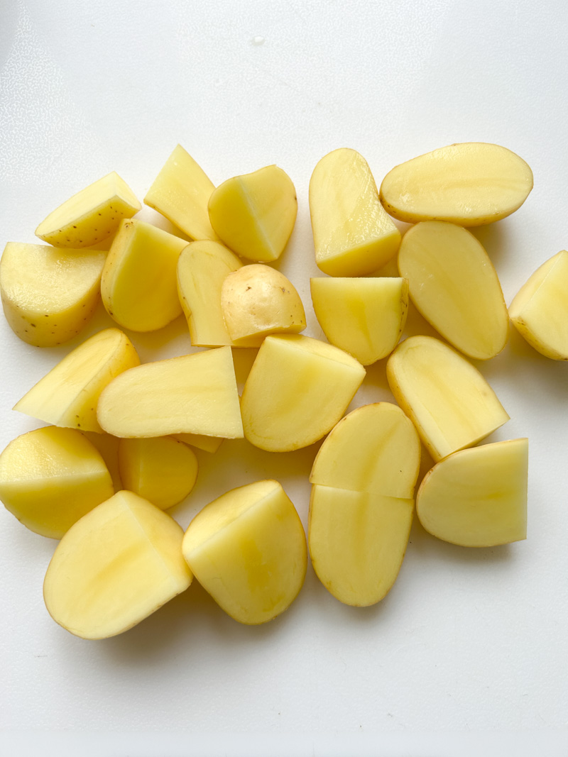 Half potatoes on a white cutting board.