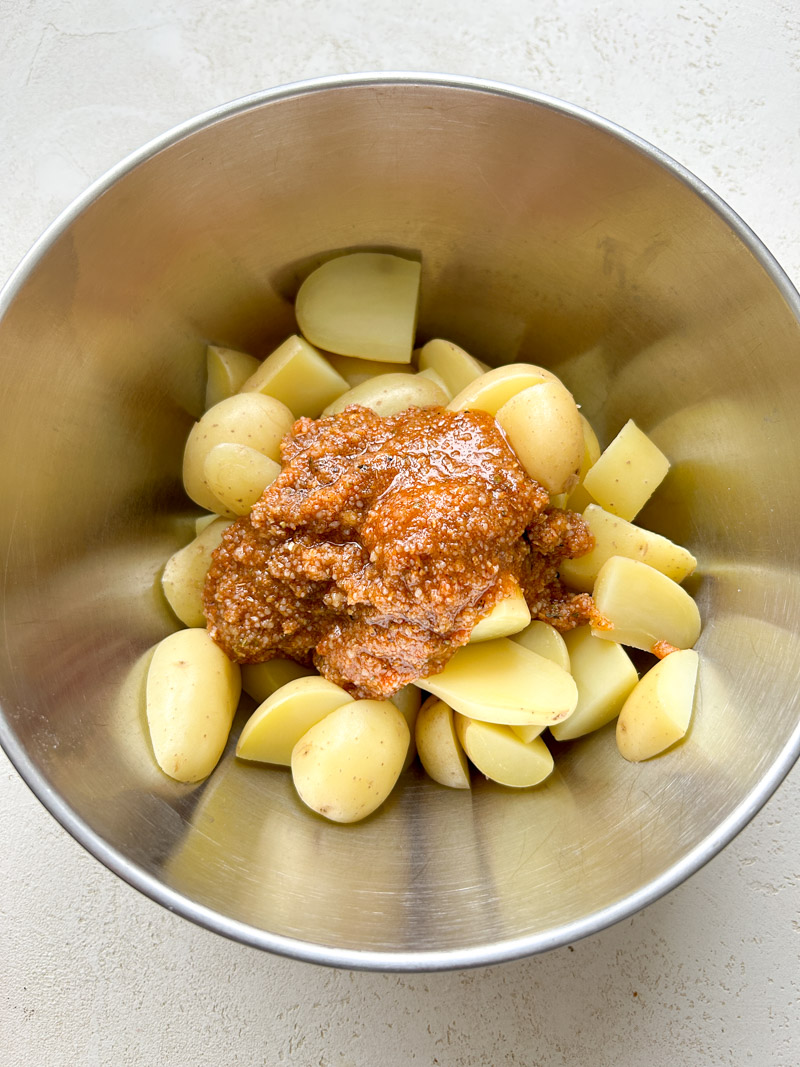 Mélange de Parmesan sur le dessus des pommes de terre, dans le bol en inox.