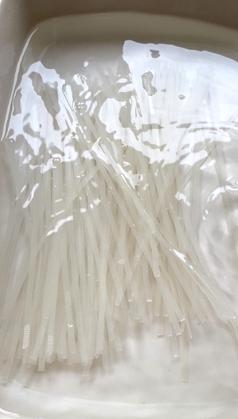 Rice noodles in a large plate of water.