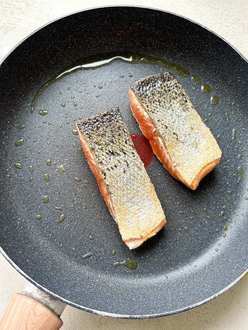 Deux filets de saumon dans une grande poêle avec de l'huile d'olive.