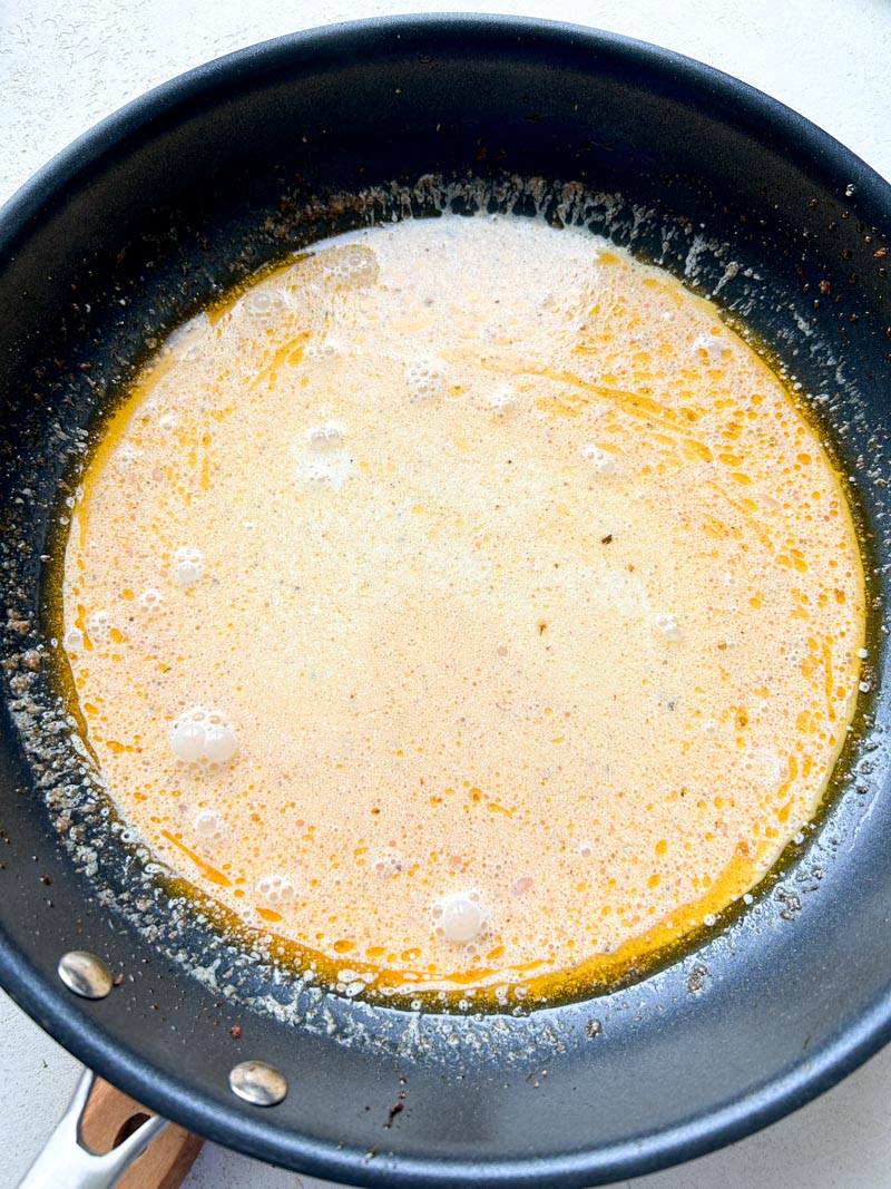 Homemade Alfredo sauce in a black frying pan.